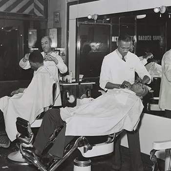 two men get a haircut in a black barbershop