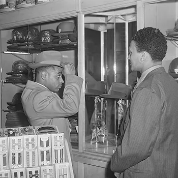 a man trying on a hat in a habadashery